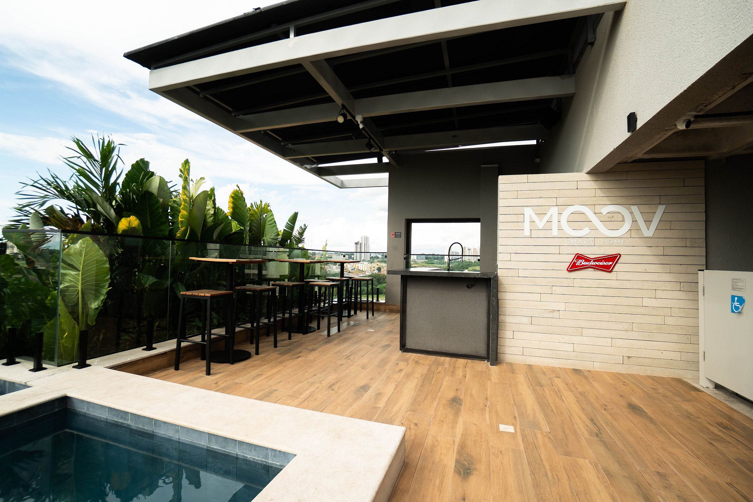 A rooftop bar with a pool, outdoor seating, and a view of the city skyline.