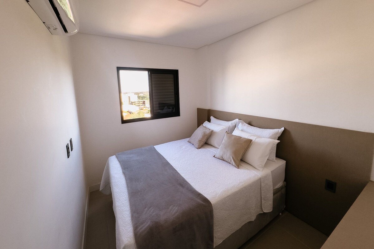 A bedroom with a bed, a window, and an air conditioning unit.