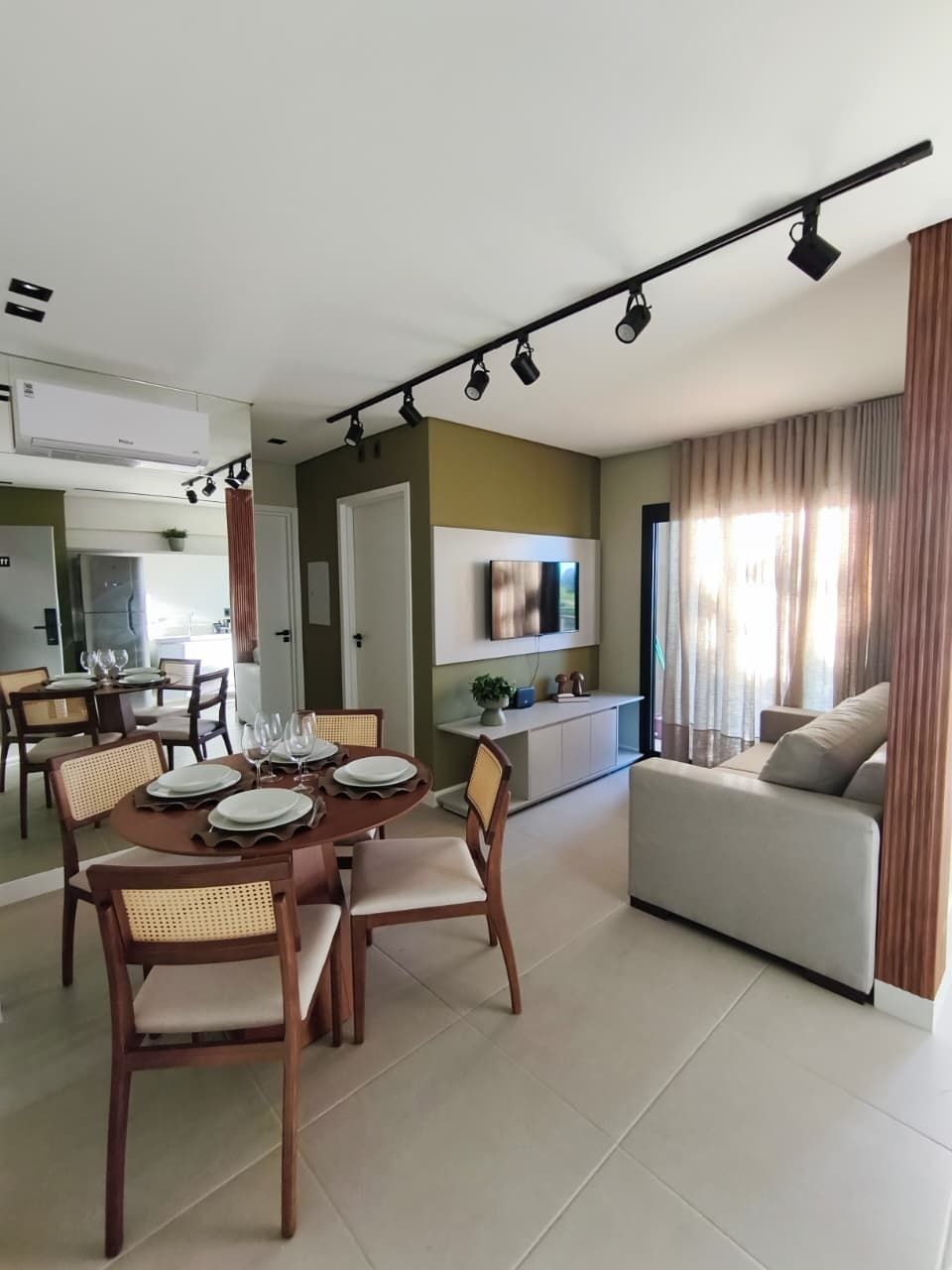 Una sala moderna con un sofá, una mesa de comedor preparada para cuatro personas y una cocina al fondo.