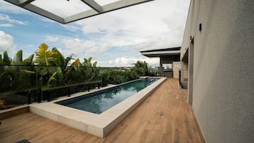 Zona de piscina al terrat amb una vista clara del perfil urbà de la ciutat, envoltada de vegetació exuberant i arquitectura moderna.