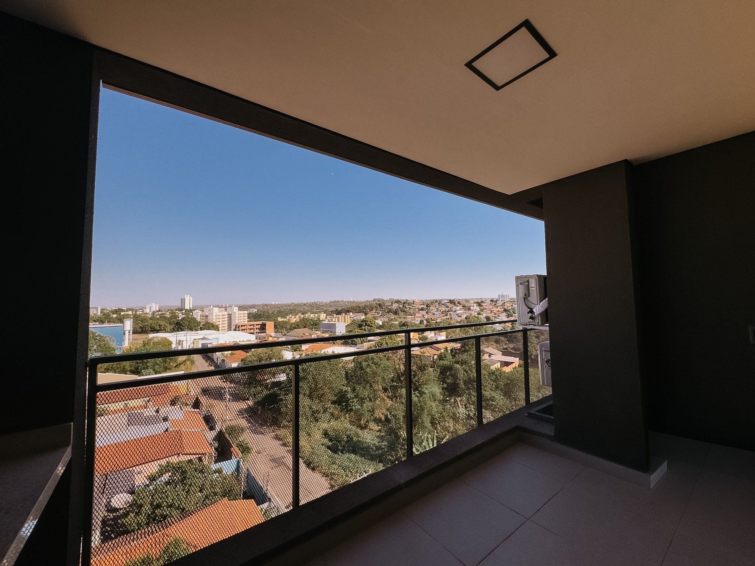 Un balcón con vistas a un paisaje urbano, que incluye edificios y zonas verdes.