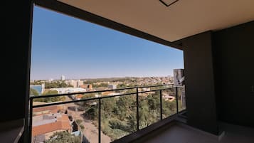Un balcón con vistas a un paisaje urbano, que incluye edificios y zonas verdes.
