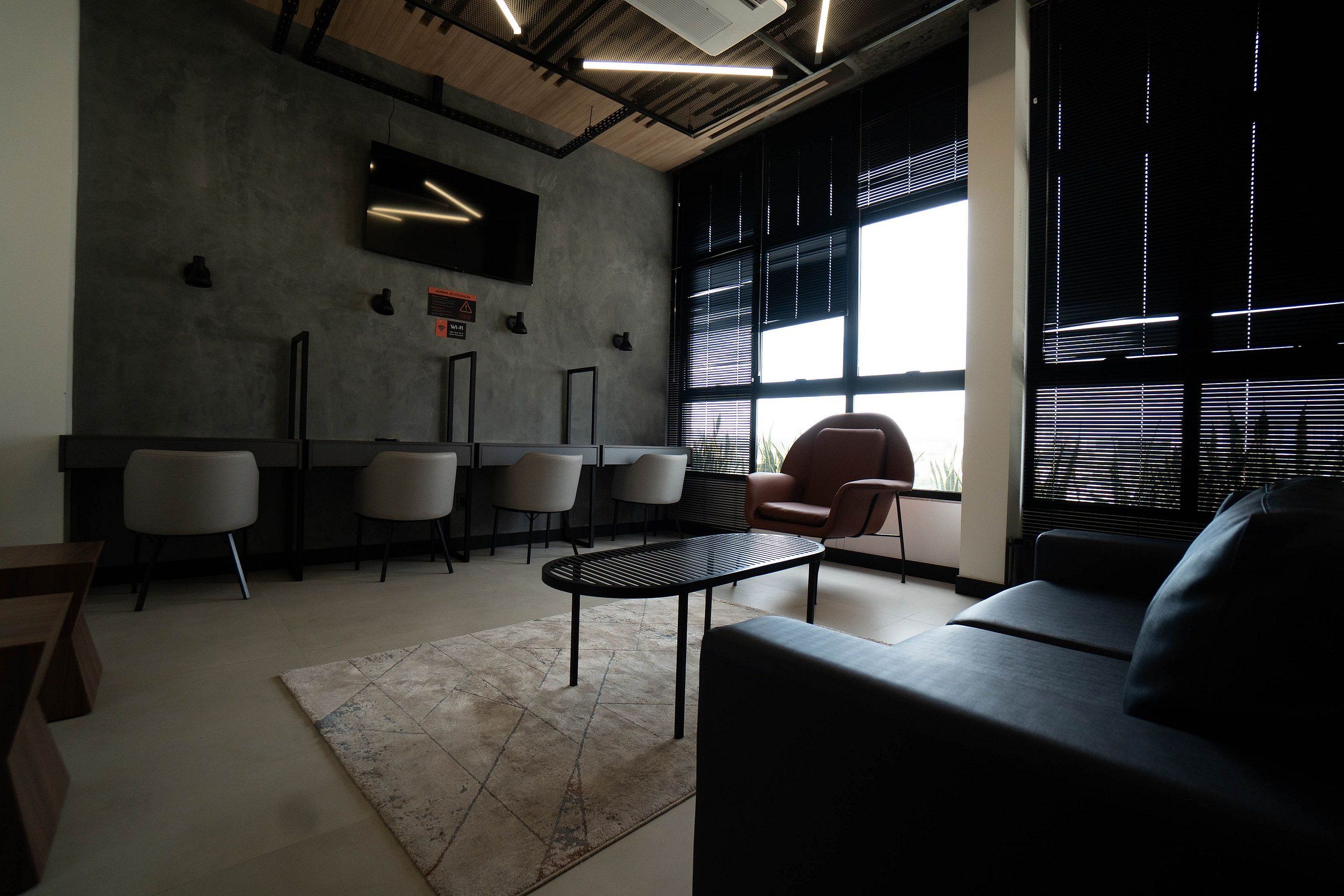 A modern office space with a black sofa, a round table, and several chairs.