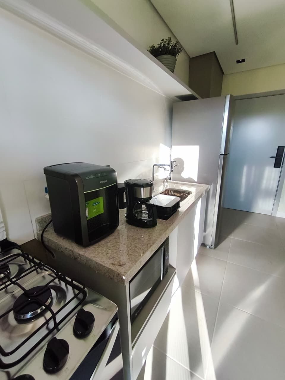 A modern kitchen with a gas stove, coffee maker, and stainless steel appliances.