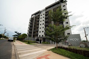 Un edificio residencial de varios pisos con un diseño moderno, con balcones y una entrada protegida por una reja.