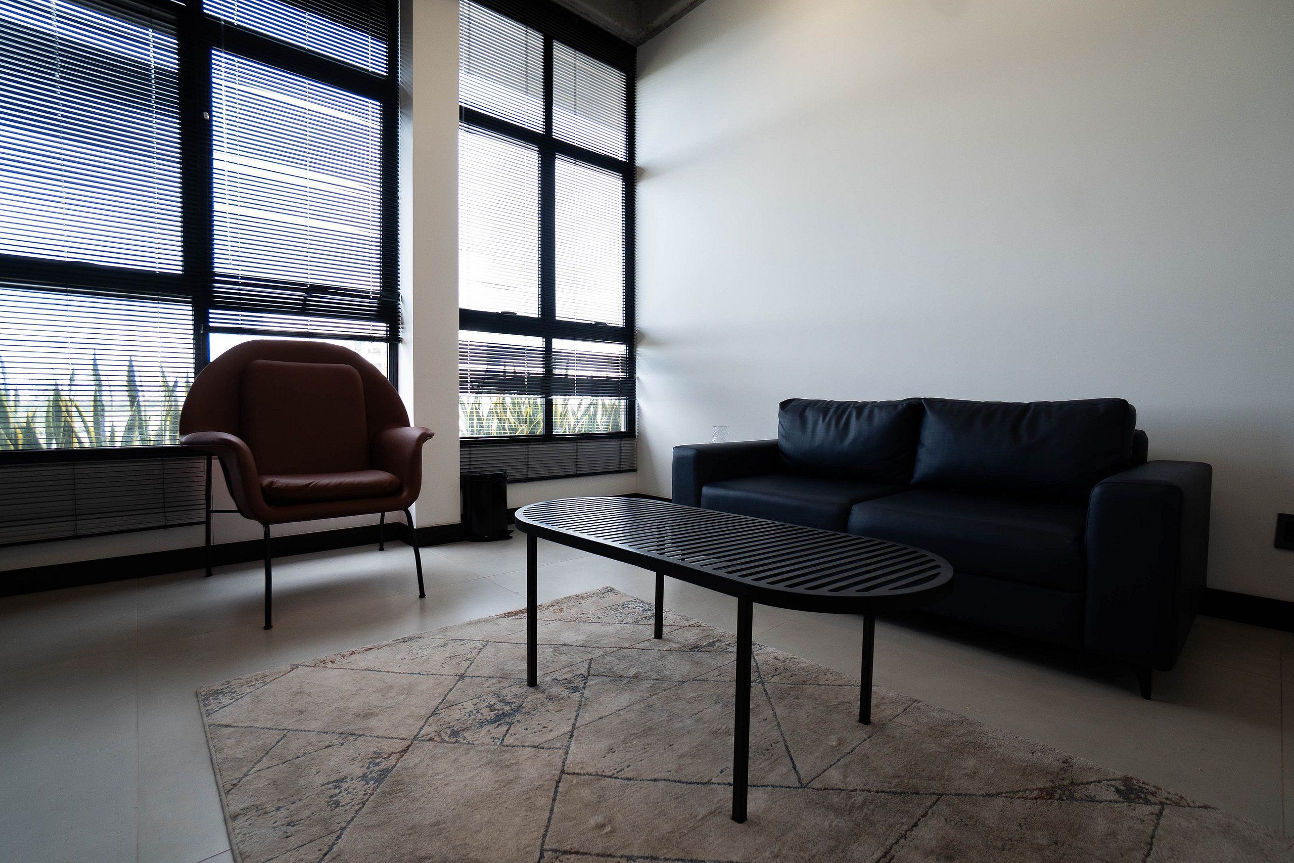 Een moderne woonkamer met een donkere bank, een bruine fauteuil en een bijzettafeltje.