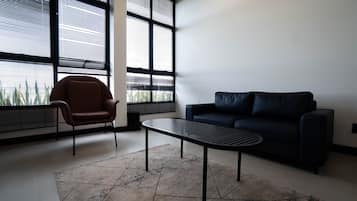 Een moderne woonkamer met een donkere bank, een bruine fauteuil en een bijzettafeltje.