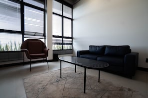 Una sala de estar moderna con un sofá oscuro, un sillón marrón y una mesita.