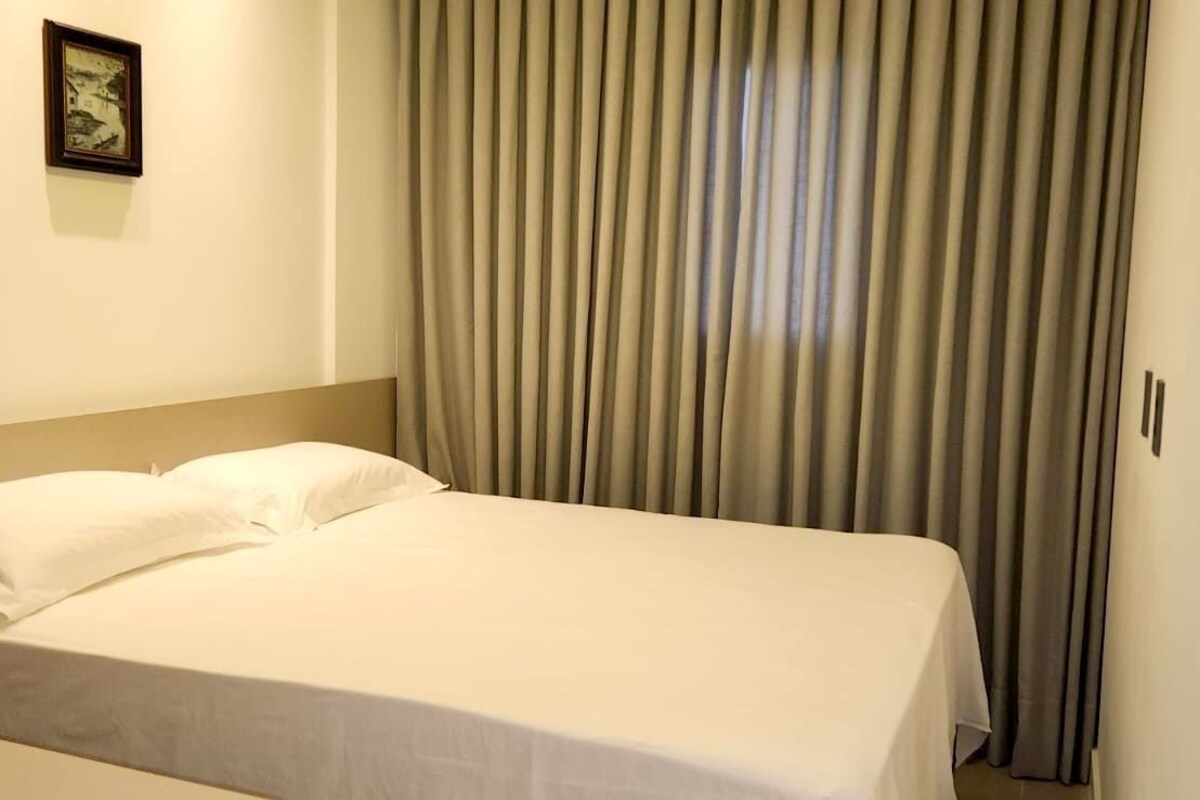 A single bed with white bedding in a room with a neutral color scheme.