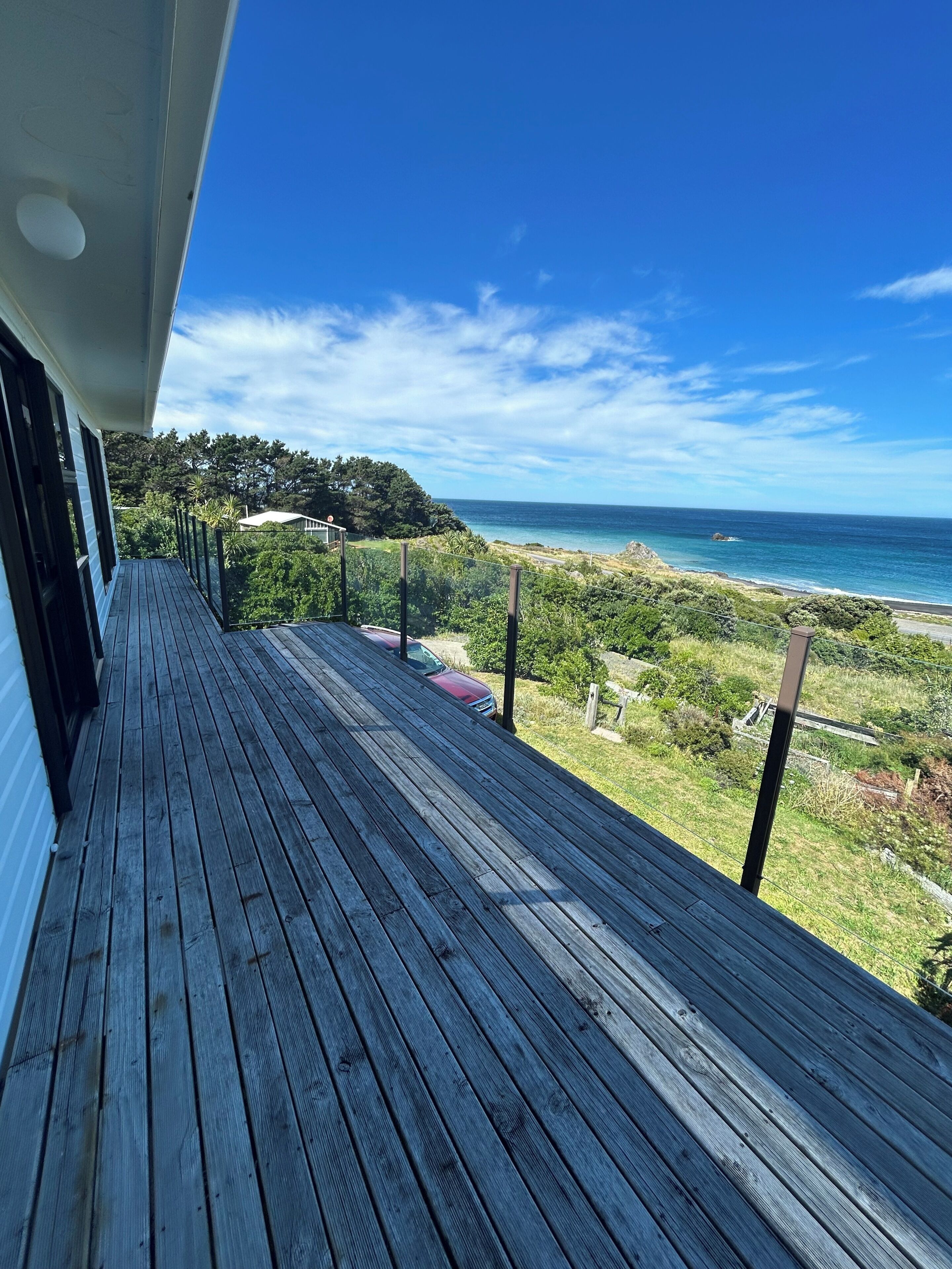 Une terrasse en bois offrant une vue sur l’océan et la verdure.