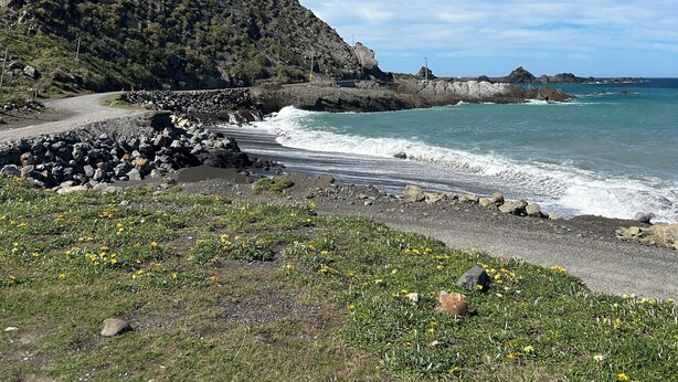 A coastal landscape with a dirt path, rocky beach, and a mountain in the background. - Ben Avon Views - Cape Palliser/Ngawi
Stunning ocean veiws, Fireplace & BBQ (Cape Palliser)