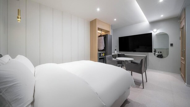 A modern hotel room with a large bed, a desk, and a TV mounted on the wall.