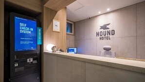 A reception desk with a self-check-in system, a framed certificate, and a logo for Hound Hotel.