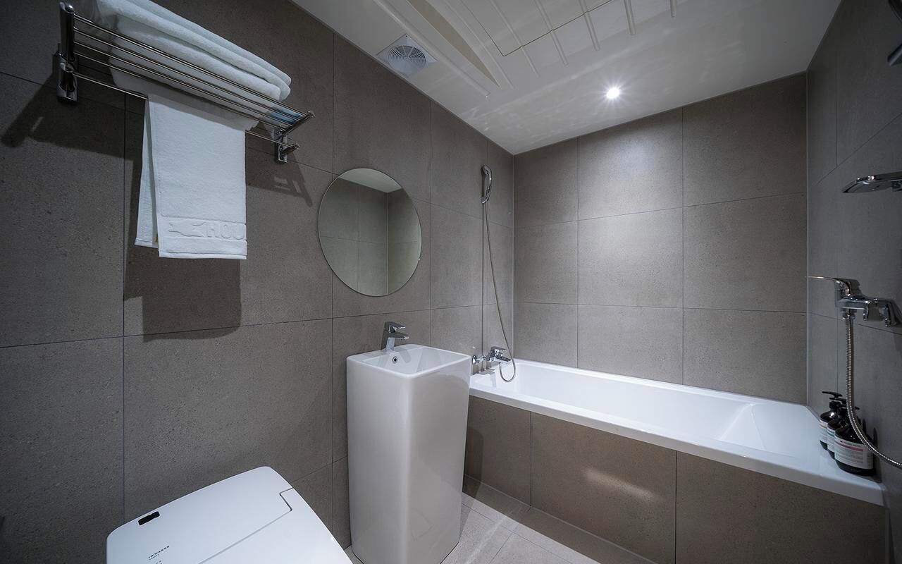 A modern bathroom with a bathtub, a sink, a mirror, and a towel rack.