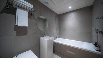 A modern bathroom with a bathtub, a sink, a mirror, and a towel rack.
