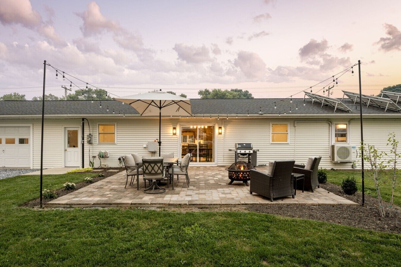 A residential property with a patio area featuring outdoor furniture, a fire pit, and solar panels on the roof.