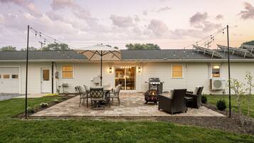 A residential property with a patio area featuring outdoor furniture, a fire pit, and solar panels on the roof.