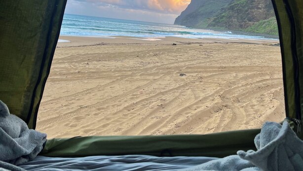 Una tenda con vista sulla spiaggia e su una montagna.