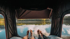Dalla tenda, vista chiara di un lago e alberi riflessi sulla tela.