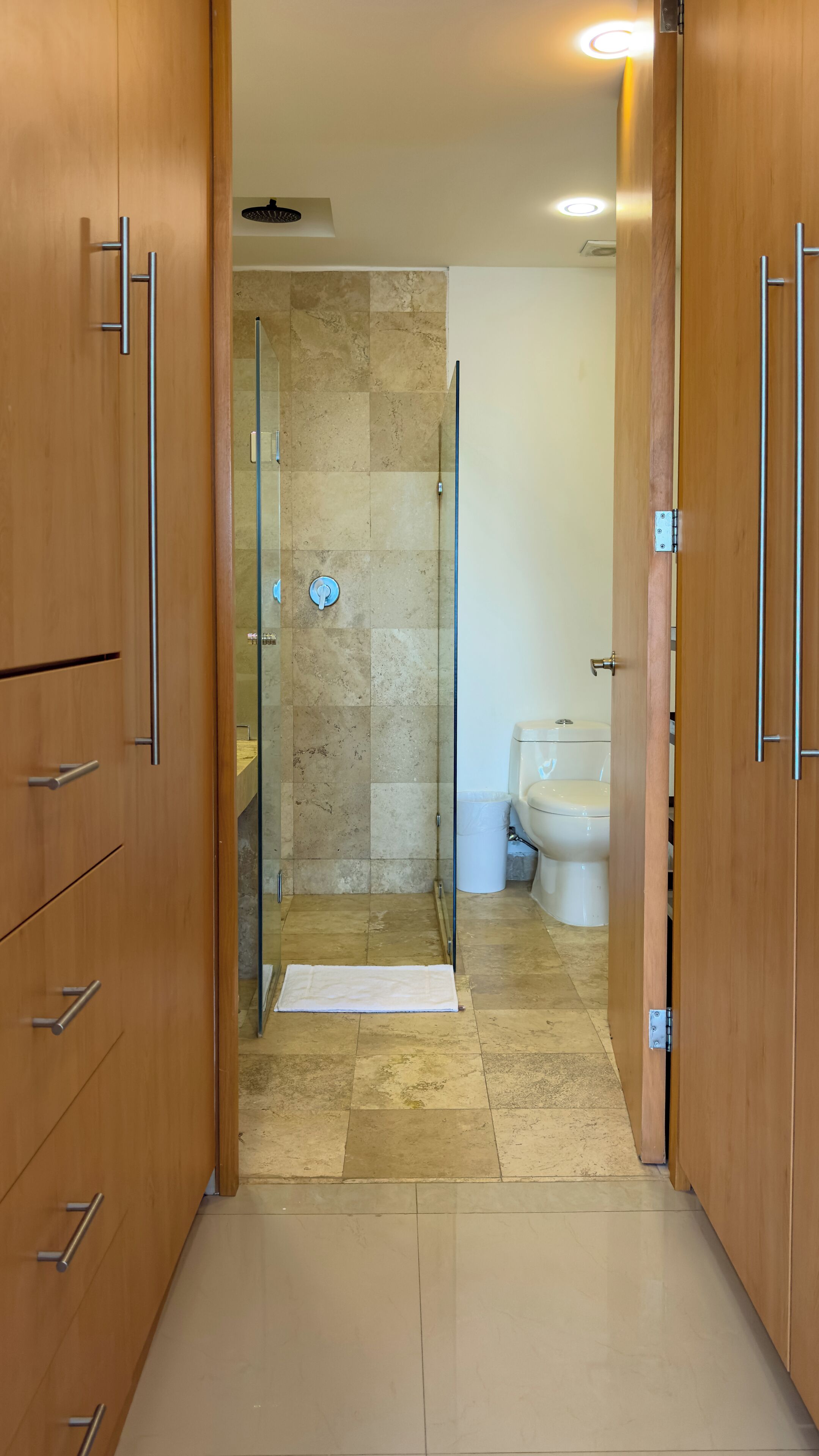 Een badkamer met een douche, toilet en een handdoek op de vloer.