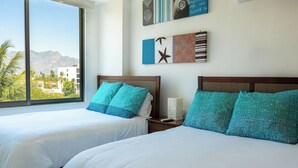 Una habitación de hotel con dos camas, un ventanal con vistas a la montaña y una obra de arte en la pared.