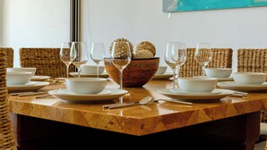 Una mesa de comedor dispuesta con cuencos, platos y copas de vino blancos, junto con un recipiente decorativo que contiene dos objetos puntiagudos.