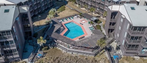 Un hotel de varios pisos con un patio central que cuenta con una piscina, rodeado de balcones y un pequeño jardín.