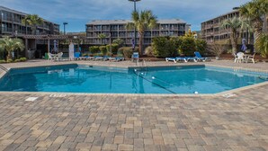 A rectangular swimming pool with lounge chairs and umbrellas, surrounded by brick flooring and palm trees. - Tilghman Beach & Racquet Club 224 (North Myrtle Beach)