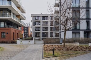 A multi-story residential building with balconies, a paved walkway, and a landscaped area with grass and shrubs. - Rakowicka Apartment with FREE PARKING (Kraków)