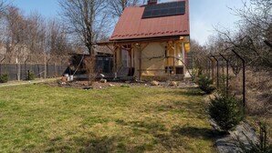 Ein Haus mit Solaranlage auf dem Dach, einem eingezäunten Garten und blauem Himmel.