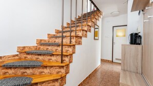 Eine Treppe mit Holzboden und Metallgeländern, die zu einem Raum mit einer Tür und einer Kaffeemaschine führt.