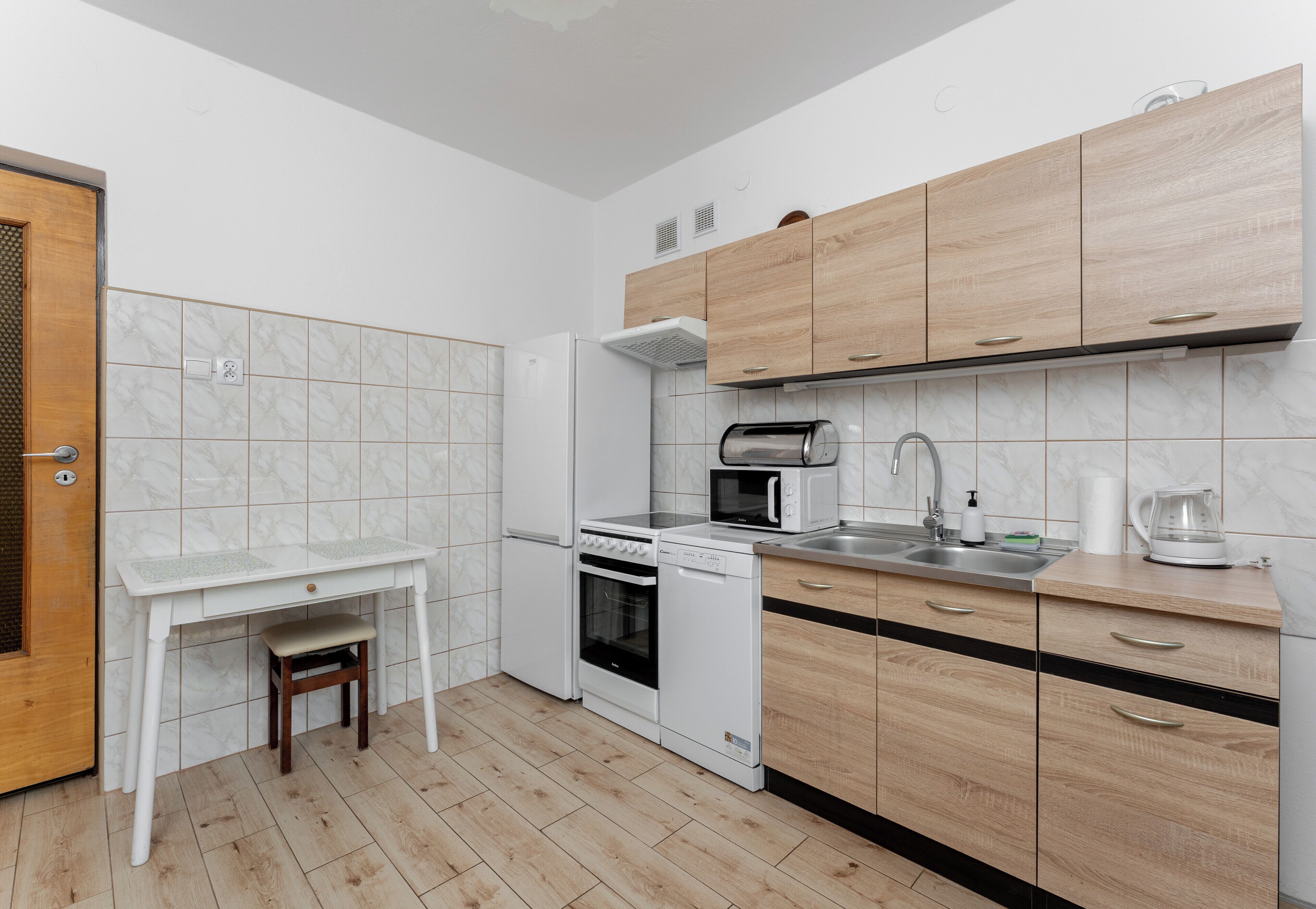 A compact kitchen with a white countertop, wooden cabinets, a built-in oven, and a microwave.