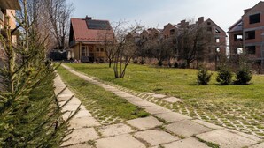Ein Wohngebiet mit einem gepflasterten Weg, einem Haus mit Holzbalkonen und rotem Dach sowie mehreren Backsteingebäuden.