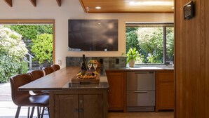 A modern kitchen with a dining area, wooden cabinets, a built-in oven, and a large window. - The Art House | Queenstown lakefront & central location (Queenstown)