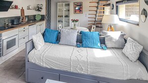 Een slaapkamer met een bed, nachtkastjes, een raam, een lamp en een kitchenette.