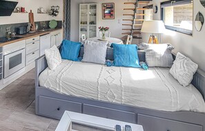 Ein Schlafzimmer mit Bett, Nachttischen, einem Fenster, einer Lampe und einer Küchenzeile.