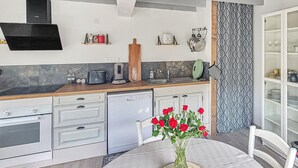 Een moderne keuken met witte kasten, een houten aanrecht en een eettafel met een vaas rode bloemen.