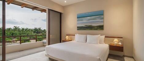 Een hotelkamer met een groot bed, uitzicht op palmbomen en een schilderij aan de muur.