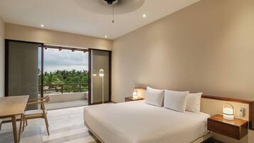 Quarto de hotel com cama, mesas de cabeceira, uma mesa com cadeiras e vista para o verde lá fora.