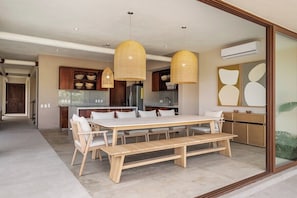 Una cocina moderna con comedor, muebles de madera e iluminación colgante.