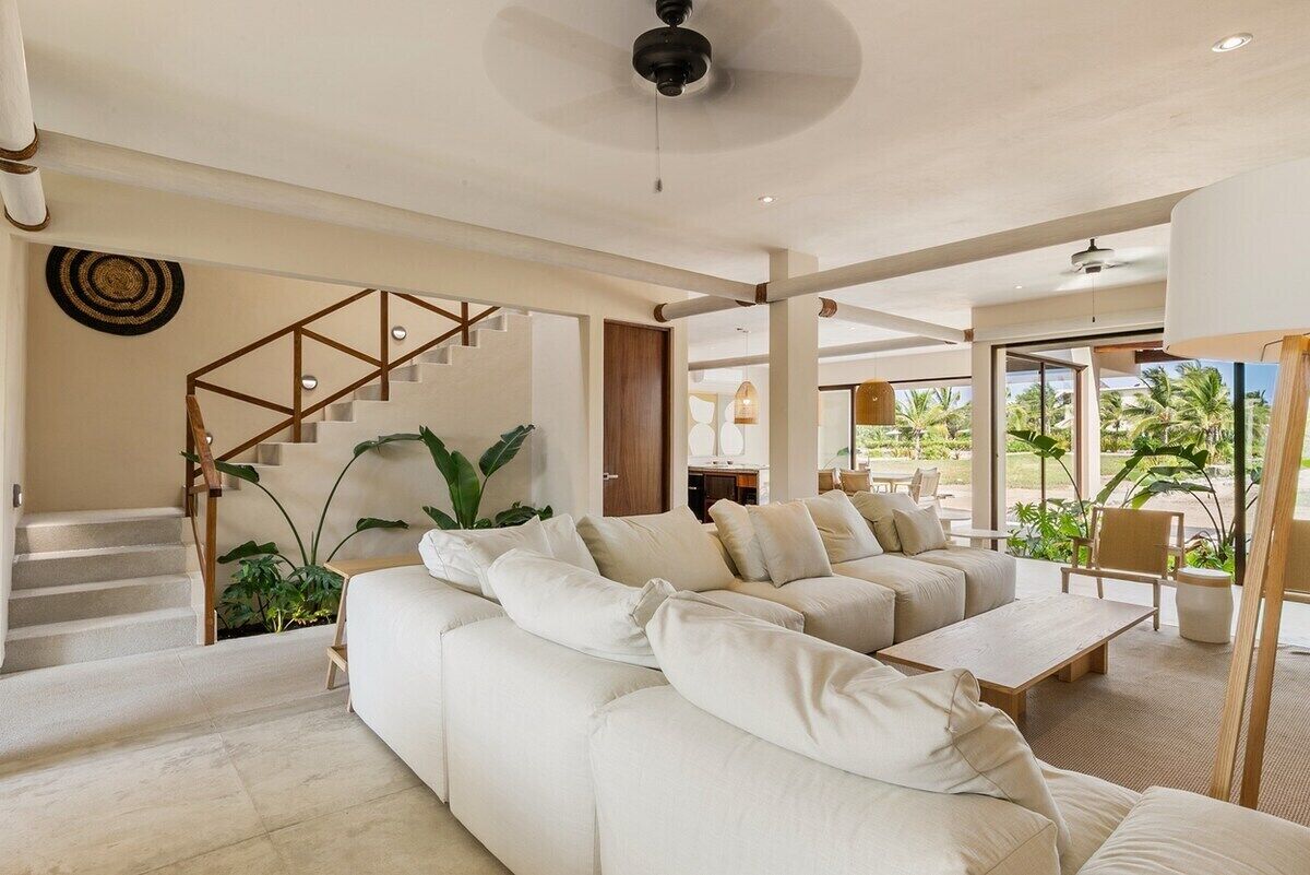 A modern living room with a sectional sofa, a coffee table, and a staircase with wooden railings.
