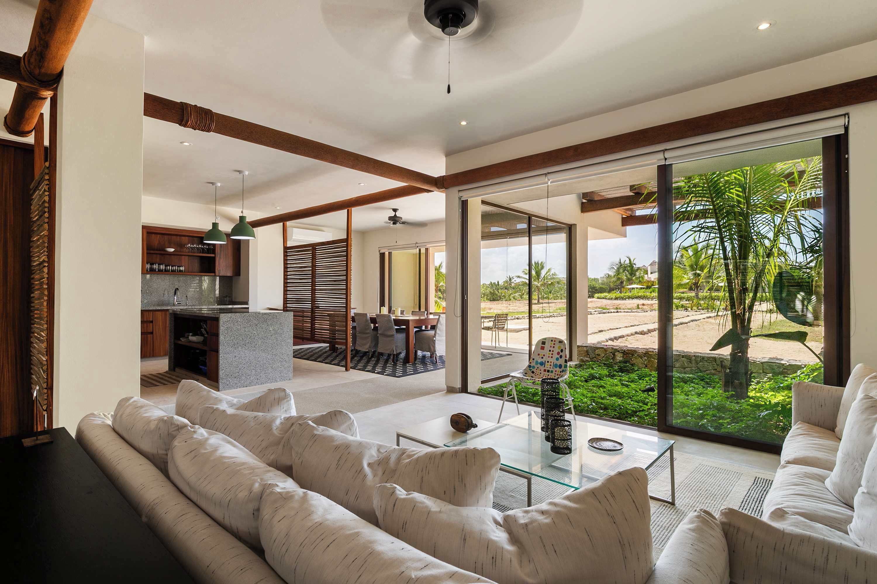 Una sala de estar moderna con una mesa de centro de vidrio, un sofá y vistas al exterior a través de amplios ventanales.