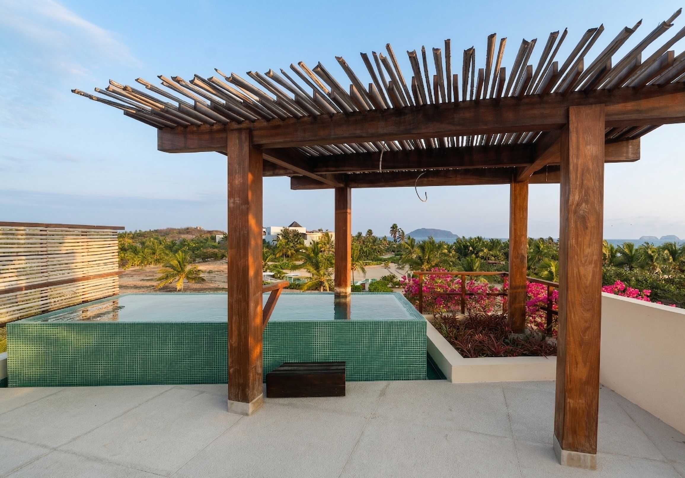 Un espace piscine aménagé sur le toit, avec une pergola, une vue sur un jardin paysager et un ciel dégagé.