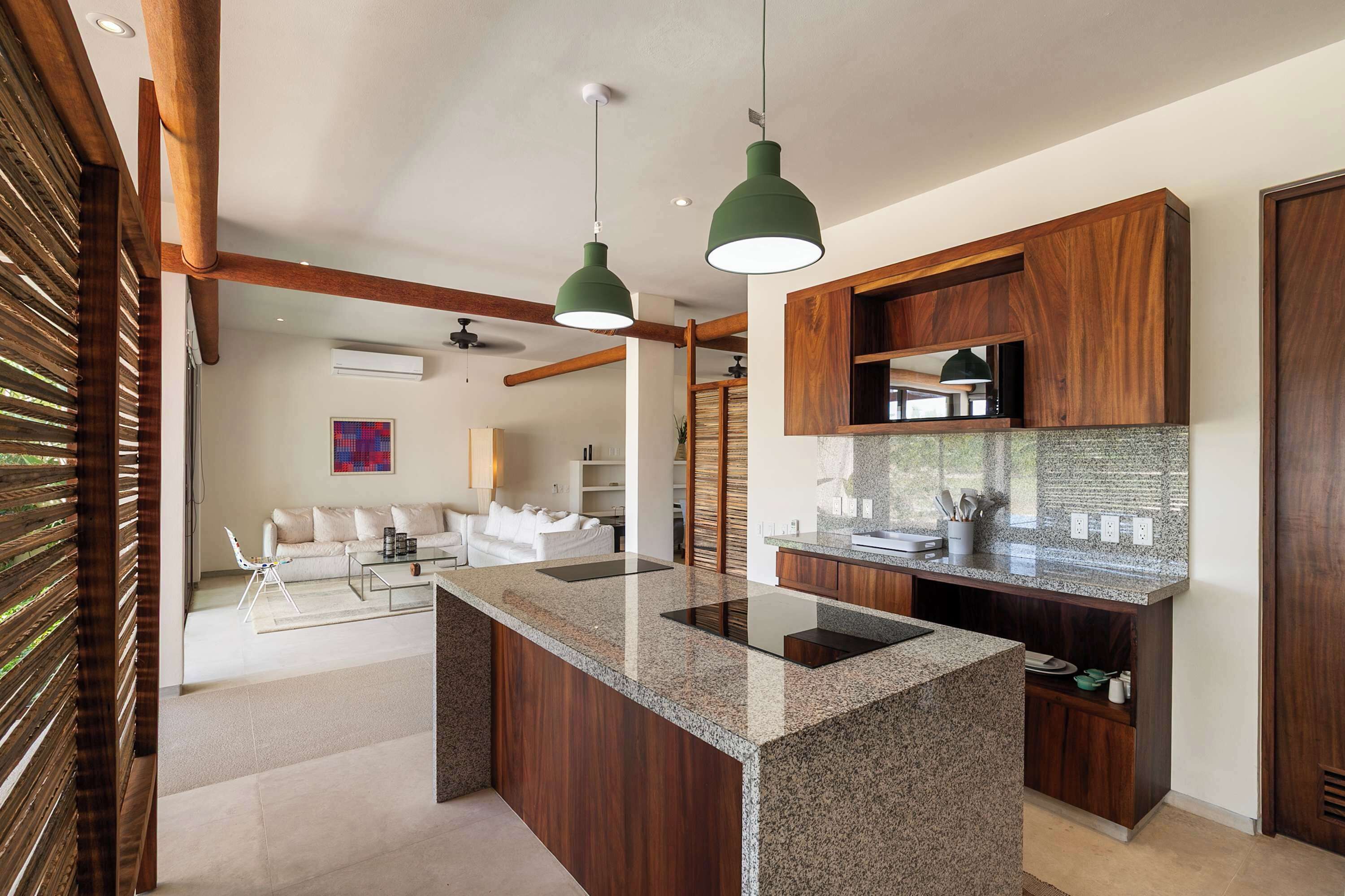 Una cocina moderna con una isla central, muebles de madera e iluminación colgante.