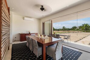 A modern dining area with a large table, chairs, and a view of the outdoors.