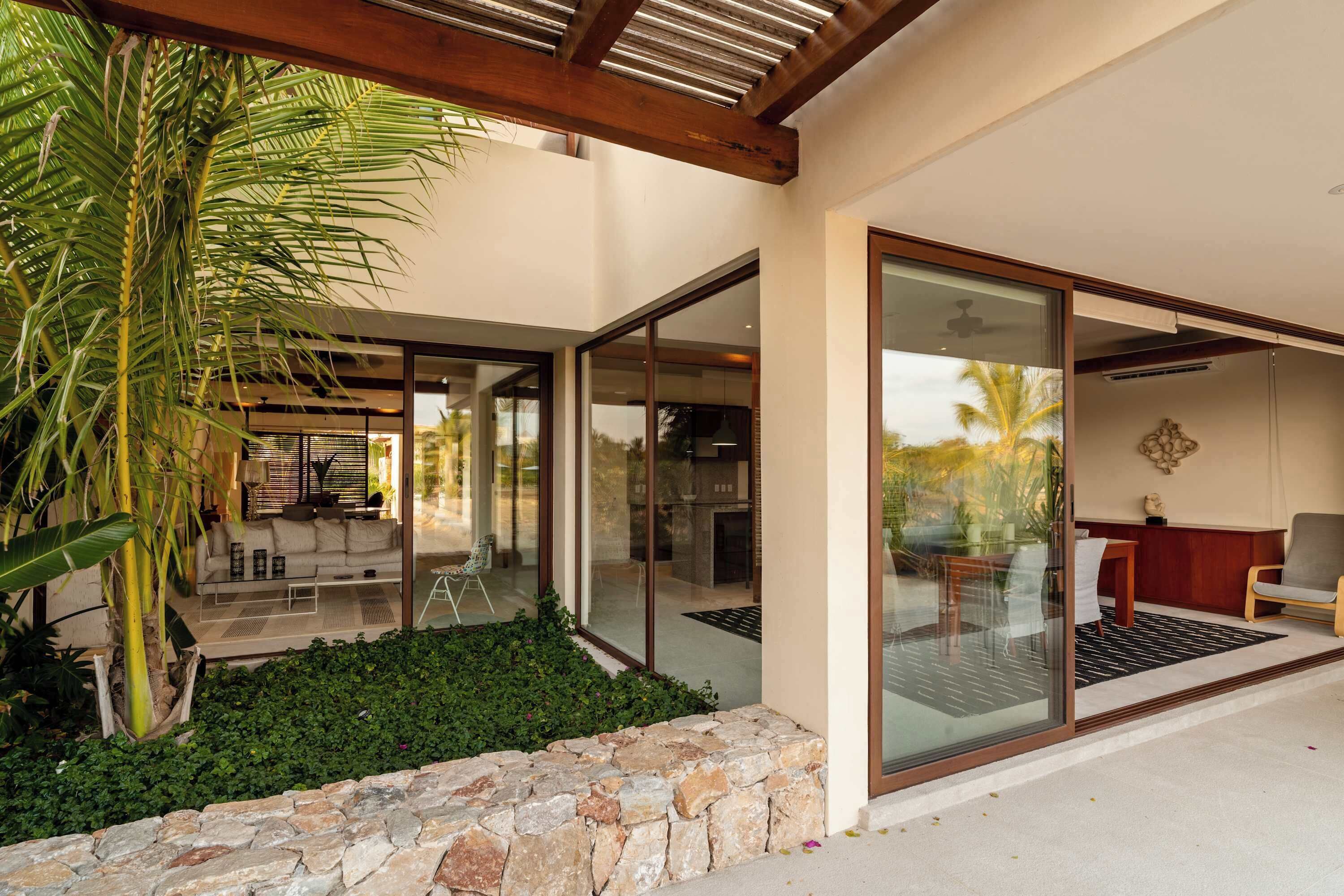 A modern house with a stone wall, a glass door leading to a patio, and a view of the outdoors.