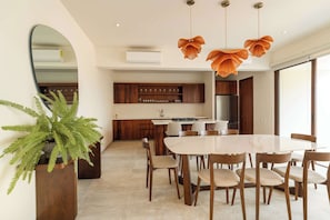 Una cocina moderna con armarios de madera, una isla central y un comedor con mesa de mármol y sillas de madera.