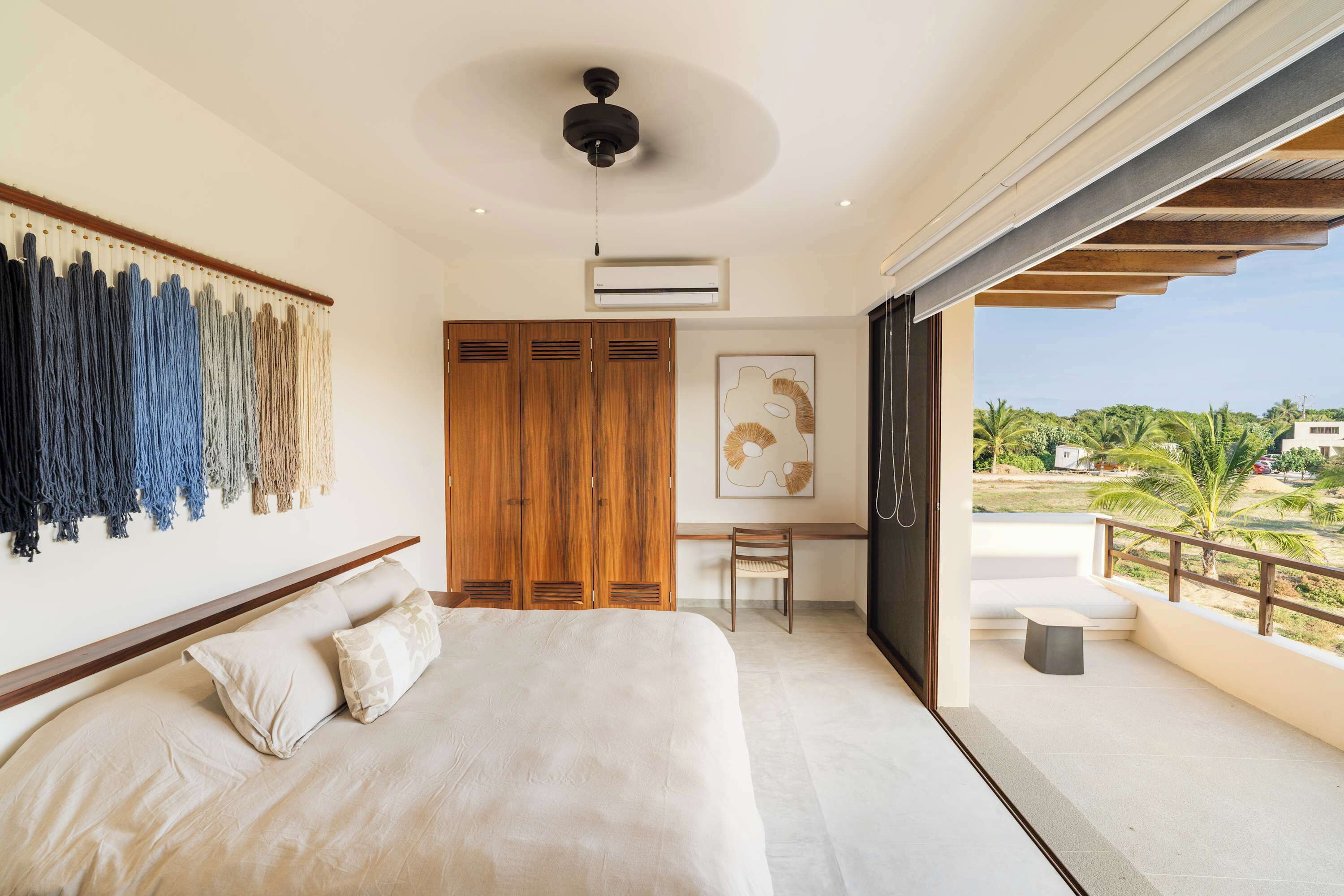 Ein Schlafzimmer mit Bett, Schreibtisch und Blick ins Freie.