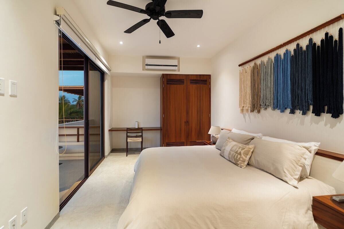 A bedroom with a bed, a desk, and a wardrobe.