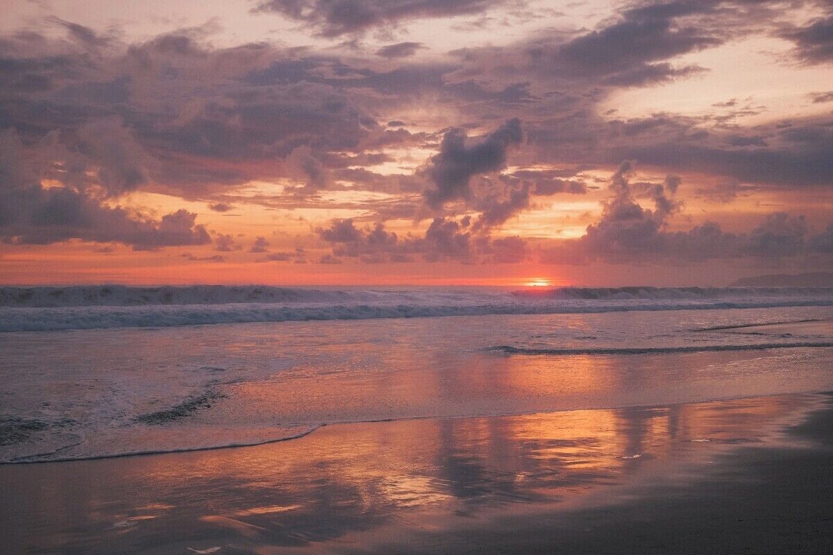 A beach scene with waves and a sunset.